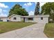 Charming single-story home with a well-maintained lawn and a cracked concrete driveway under a clear blue sky at 6335 Kings Ct, New Port Richey, FL 34653