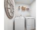 Modern laundry room featuring a washer, dryer, and storage shelves with laundry supplies at 6770 Pebblebrooke Way, Zephyrhills, FL 33541