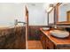 Bathroom featuring double stone sinks, wooden cabinets, and brown tile at 7230 17Th N Ln, St Petersburg, FL 33702