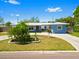 Well-maintained one-story home with a blue exterior, white trim, a circular driveway, and verdant landscaping at 7230 17Th N Ln, St Petersburg, FL 33702