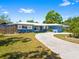 Charming single-story home features a blue exterior, manicured lawn, mature landscaping, and a long driveway at 7230 17Th N Ln, St Petersburg, FL 33702