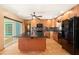 Kitchen with a large island, black appliances, wood cabinets, and a door to the patio and pool at 7230 17Th N Ln, St Petersburg, FL 33702