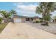 Exterior shot of home featuring a gravel yard, palm trees, solar panels, and a driveway at 7341 Bimini Dr, Port Richey, FL 34668