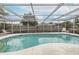 Enclosed pool with screen, metal frame, blue tile trim and a view of the blue sky and clouds at 7341 Bimini Dr, Port Richey, FL 34668