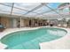 A blue tiled in ground enclosed pool with a seating and patio area at 7341 Bimini Dr, Port Richey, FL 34668