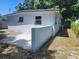 Side view of a single story house with a concrete patio and fenced yard with a stucco style exterior at 825 Lincoln Ave, Tarpon Springs, FL 34689