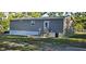 Gray house shows its exterior with a concrete patio with steps, a classic white door, and well-maintained lawn at 9625 Pat St, Hudson, FL 34669