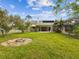 Expansive backyard with fire pit, screened lanai, and lush greenery, perfect for outdoor entertaining at 10318 Piper Dr, New Port Richey, FL 34654
