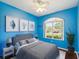 Vibrant blue bedroom with modern decor, a comfortable queen bed, and ample natural light from a large window at 10318 Piper Dr, New Port Richey, FL 34654