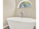 A close up of the soaking tub next to an arched window in the bathroom at 10423 Ashley Oaks Dr, Riverview, FL 33578