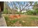 A backyard shows a large grassy area surrounded by trees and a stacked wood pile on an orange mulch bed at 10531 Lakeview Dr, New Port Richey, FL 34654