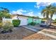 Charming single-story home featuring an attached garage, driveway, and palm tree landscaping at 1054 Embassy Ave, Spring Hill, FL 34606