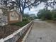 Community entrance featuring a stone sign, guardhouse, and decorative stone wall at 12119 Sunny Glen Ln # G2, Hudson, FL 34669