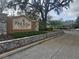 Community entrance featuring a stone sign, guardhouse, and decorative stone wall at 12119 Sunny Glen Ln # G2, Hudson, FL 34669