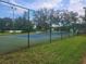 Fenced tennis court with vibrant blue surface and lush greenery, perfect for sports enthusiasts at 12119 Sunny Glen Ln # G2, Hudson, FL 34669