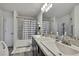 Bright bathroom with dual sinks, granite countertop, tub/shower, gray flooring, and good lighting at 12848 Hilary St, Spring Hill, FL 34609