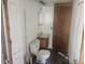 Unfinished bathroom featuring an outdated toilet and vanity, bare walls, and peeling floor tiles at 13120 Davista Ave, New Port Richey, FL 34654