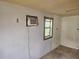 Image displays a small interior bedroom with peeling paint, and an outdated window air conditioning unit at 13120 Davista Ave, New Port Richey, FL 34654