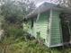 Green mobile home covered in overgrown vegetation showing signs of disrepair and neglect at 13120 Davista Ave, New Port Richey, FL 34654
