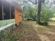 Side view of property with wood and green siding, and mature trees at 13120 Davista Ave, New Port Richey, FL 34654