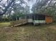 Exterior view of a green house with a ramp entrance surrounded by mature trees at 13120 Davista Ave, New Port Richey, FL 34654