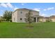 Backyard of a two-story home featuring a well-manicured lawn and a young tree, showcasing the outdoor space at 13619 Hunters Point St, Spring Hill, FL 34609