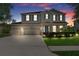 Inviting two-story home at dusk featuring a three-car garage, manicured lawn and charming curb appeal at 13619 Hunters Point St, Spring Hill, FL 34609