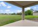 View from the covered patio overlooking a spacious green backyard with trees and a glimpse of other houses in the distance at 13619 Hunters Point St, Spring Hill, FL 34609