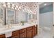 Well-lit Primary bathroom with a double sink vanity, mirrors, and tub, featuring decorative wallpaper at 1473 Sail Harbor Cir, Tarpon Springs, FL 34689