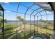 A screened-in patio features views of the serene lawn, water and tropical landscaping at 1473 Sail Harbor Cir, Tarpon Springs, FL 34689