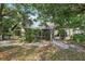 A beige house can be seen from the backyard surrounded by trees and foliage, with a screened in porch area at 1641 Bayfield Ct, Trinity, FL 34655