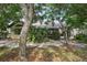 A beige house can be seen from the backyard surrounded by trees and foliage, with a screened in porch area at 1641 Bayfield Ct, Trinity, FL 34655
