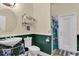 Well-lit bathroom featuring a white commode and sink, sea-green lower-half walls, and shower at 18328 Treehaven Dr, Hudson, FL 34667