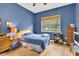 Bedroom featuring blue walls, wood-look floors, and a window with blinds at 18328 Treehaven Dr, Hudson, FL 34667