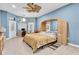 Bright main bedroom with blue walls, ceiling fan, and desk area with natural lighting at 18328 Treehaven Dr, Hudson, FL 34667