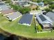 An aerial view of a backyard with a lush green lawn, a dark gray roof, and a pond just beyond the property line at 18456 Merseyside Loop, Land O Lakes, FL 34638