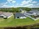 An aerial view of a backyard with a lush green lawn, a dark gray roof, and a pond just beyond the property line at 18456 Merseyside Loop, Land O Lakes, FL 34638