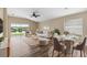 Open-concept living room with large windows and a view of the pond. Features a dining area, ceiling fan and neutral paint at 18456 Merseyside Loop, Land O Lakes, FL 34638