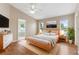 Bright main bedroom with ensuite bath, wood floor, ceiling fan, and light wood bed frame at 18456 Merseyside Loop, Land O Lakes, FL 34638
