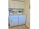 Bright laundry room with white washer, dryer, and overhead cabinets for ample storage at 24862 Us Highway 19 N # 203, Clearwater, FL 33763
