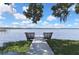 Scenic view of the lake showcases a dock and bench surrounded by vegetation beneath a bright, cloudy sky at 279 Maple Ave, Palm Harbor, FL 34684
