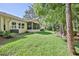 Expansive backyard featuring lush green grass, a screened lanai, and mature trees for ample shade at 3013 Appleblossom Trl, Spring Hill, FL 34606