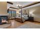 Luxurious primary bedroom with a cozy fireplace, four-poster bed, hardwood floors, and natural light from shuttered windows at 3026 Wentworth Way, Tarpon Springs, FL 34688