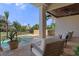 Covered patio features seating, a ceiling fan, and a tranquil view of the pool and manicured lawn at 3026 Wentworth Way, Tarpon Springs, FL 34688