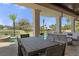 Covered outdoor patio with ample seating, a large dining table, and view of the pool and lush landscaping at 3026 Wentworth Way, Tarpon Springs, FL 34688