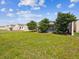 The backyard is beautifully landscaped with green grass, trees, and a screened in pool at 305 Royal Palm Way, Spring Hill, FL 34608