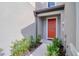A charming front entryway features a bright red door, lush landscaping, and inviting curb appeal at 31718 Blue Passing Loop, Wesley Chapel, FL 33545