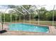 Sparkling in-ground pool in a screened enclosure is surrounded by lush landscaping and a brick paver deck at 4475 Rachel Blvd, Spring Hill, FL 34607