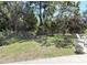 View of the backyard with green grass, mature trees, patio furniture, and barbecue in a pleasant and quiet setting at 4748 Yellowstone Dr, New Port Richey, FL 34655
