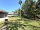 Expansive backyard featuring lush green grass, mature trees, and partial view of the screened in patio area at 4748 Yellowstone Dr, New Port Richey, FL 34655